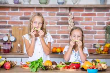 Mutfakta taze sebzelerle iki küçük kız. Sağlıklı gıda konsepti. Mutlu kardeşler..