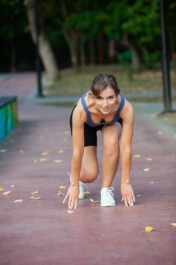 Spor giyimli genç bir bayan dışarıda esneme egzersizleri yapıyor. Parkta spor yapan genç bir kızın portresi..