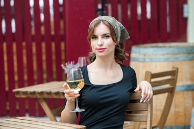 Güzel genç bir kadın bir restoranın terasında beyaz şarap içiyor. İşten sonra bir bardak şarapla dinleniyorum. Bekar kadın eğleniyor..