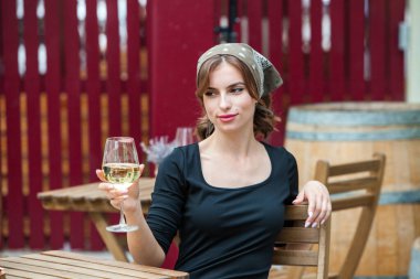 Güzel genç bir kadın bir restoranın terasında beyaz şarap içiyor. İşten sonra bir bardak şarapla dinleniyorum. Bekar kadın eğleniyor..