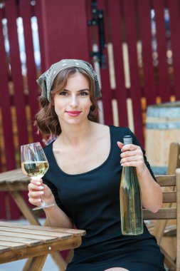 Güzel genç bir kadın bir restoranın terasında beyaz şarap içiyor. İşten sonra bir bardak şarapla dinleniyorum. Bekar kadın eğleniyor..