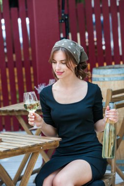Güzel genç bir kadın bir restoranın terasında beyaz şarap içiyor. İşten sonra bir bardak şarapla dinleniyorum. Bekar kadın eğleniyor..