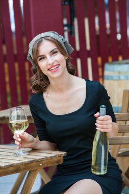 Güzel genç bir kadın bir restoranın terasında beyaz şarap içiyor. İşten sonra bir bardak şarapla dinleniyorum. Bekar kadın eğleniyor..