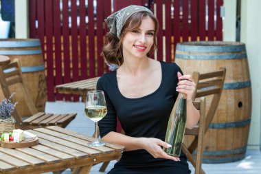 Güzel genç bir kadın bir restoranın terasında beyaz şarap içiyor. İşten sonra bir bardak şarapla dinleniyorum. Bekar kadın eğleniyor..