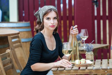 Güzel genç bir kadın bir restoranın terasında beyaz şarap içiyor. İşten sonra bir bardak şarapla dinleniyorum. Bekar kadın eğleniyor..