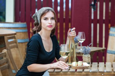 Güzel genç bir kadın bir restoranın terasında beyaz şarap içiyor. İşten sonra bir bardak şarapla dinleniyorum. Bekar kadın eğleniyor..