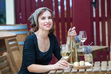 Güzel genç bir kadın bir restoranın terasında beyaz şarap içiyor. İşten sonra bir bardak şarapla dinleniyorum. Bekar kadın eğleniyor..