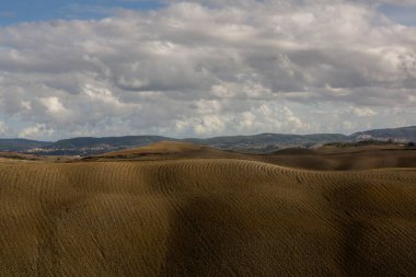 Tuscany, İtalya 'da hasat edilmiş tarlalar ve çayırlar. Sonbahar günbatımında dalgalı kır manzarası. Tarımsal mevsim için ekilebilir arazi hazır..