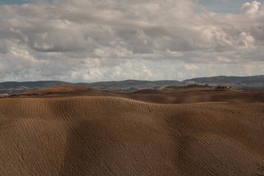 Tuscany, İtalya 'da hasat edilmiş tarlalar ve çayırlar. Sonbahar günbatımında dalgalı kır manzarası. Tarımsal mevsim için ekilebilir arazi hazır..