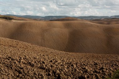 Tuscany, İtalya 'da hasat edilmiş tarlalar ve çayırlar. Sonbahar günbatımında dalgalı kır manzarası. Tarımsal mevsim için ekilebilir arazi hazır..