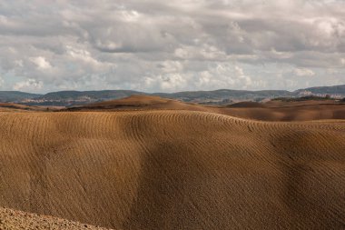 Tuscany, İtalya 'da hasat edilmiş tarlalar ve çayırlar. Sonbahar günbatımında dalgalı kır manzarası. Tarımsal mevsim için ekilebilir arazi hazır..