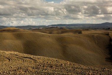 Tuscany, İtalya 'da hasat edilmiş tarlalar ve çayırlar. Sonbahar günbatımında dalgalı kır manzarası. Tarımsal mevsim için ekilebilir arazi hazır..