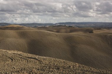 Tuscany, İtalya 'da hasat edilmiş tarlalar ve çayırlar. Sonbahar günbatımında dalgalı kır manzarası. Tarımsal mevsim için ekilebilir arazi hazır..