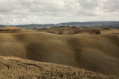 Tuscany, İtalya 'da hasat edilmiş tarlalar ve çayırlar. Sonbahar günbatımında dalgalı kır manzarası. Tarımsal mevsim için ekilebilir arazi hazır..