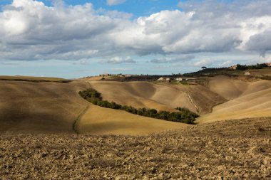Tuscany, İtalya 'da hasat edilmiş tarlalar ve çayırlar. Sonbahar günbatımında dalgalı kır manzarası. Tarımsal mevsim için ekilebilir arazi hazır..