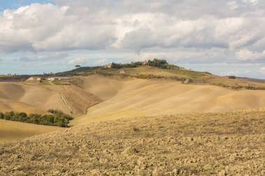 Tuscany, İtalya 'da hasat edilmiş tarlalar ve çayırlar. Sonbahar günbatımında dalgalı kır manzarası. Tarımsal mevsim için ekilebilir arazi hazır..
