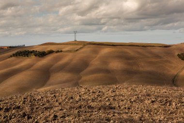 Tuscany, İtalya 'da hasat edilmiş tarlalar ve çayırlar. Sonbahar günbatımında dalgalı kır manzarası. Tarımsal mevsim için ekilebilir arazi hazır..