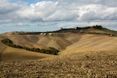 Tuscany, İtalya 'da hasat edilmiş tarlalar ve çayırlar. Sonbahar günbatımında dalgalı kır manzarası. Tarımsal mevsim için ekilebilir arazi hazır..