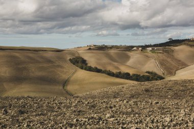 Tuscany, İtalya 'da hasat edilmiş tarlalar ve çayırlar. Sonbahar günbatımında dalgalı kır manzarası. Tarımsal mevsim için ekilebilir arazi hazır..