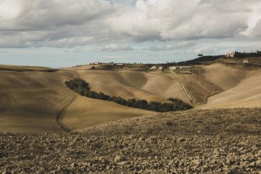 Tuscany, İtalya 'da hasat edilmiş tarlalar ve çayırlar. Sonbahar günbatımında dalgalı kır manzarası. Tarımsal mevsim için ekilebilir arazi hazır..