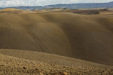 Tuscany, İtalya 'da hasat edilmiş tarlalar ve çayırlar. Sonbahar günbatımında dalgalı kır manzarası. Tarımsal mevsim için ekilebilir arazi hazır..