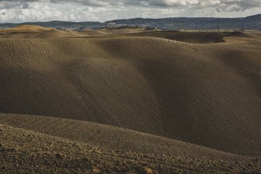 Tuscany, İtalya 'da hasat edilmiş tarlalar ve çayırlar. Sonbahar günbatımında dalgalı kır manzarası. Tarımsal mevsim için ekilebilir arazi hazır..