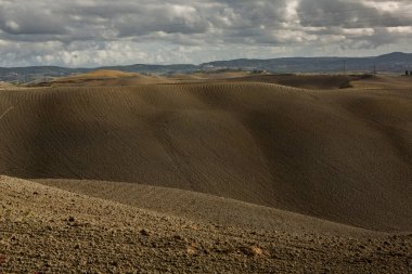 Tuscany, İtalya 'da hasat edilmiş tarlalar ve çayırlar. Sonbahar günbatımında dalgalı kır manzarası. Tarımsal mevsim için ekilebilir arazi hazır..
