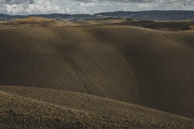 Tuscany, İtalya 'da hasat edilmiş tarlalar ve çayırlar. Sonbahar günbatımında dalgalı kır manzarası. Tarımsal mevsim için ekilebilir arazi hazır..
