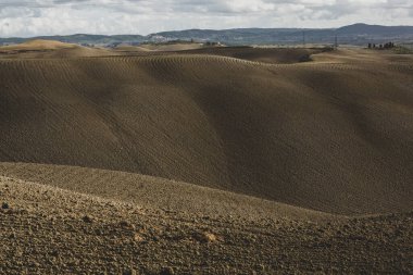 Tuscany, İtalya 'da hasat edilmiş tarlalar ve çayırlar. Sonbahar günbatımında dalgalı kır manzarası. Tarımsal mevsim için ekilebilir arazi hazır..