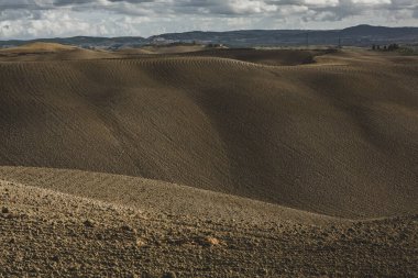 Tuscany, İtalya 'da hasat edilmiş tarlalar ve çayırlar. Sonbahar günbatımında dalgalı kır manzarası. Tarımsal mevsim için ekilebilir arazi hazır..