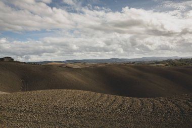 Tuscany, İtalya 'da hasat edilmiş tarlalar ve çayırlar. Sonbahar günbatımında dalgalı kır manzarası. Tarımsal mevsim için ekilebilir arazi hazır..