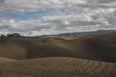 Tuscany, İtalya 'da hasat edilmiş tarlalar ve çayırlar. Sonbahar günbatımında dalgalı kır manzarası. Tarımsal mevsim için ekilebilir arazi hazır..