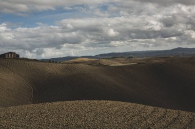 Tuscany, İtalya 'da hasat edilmiş tarlalar ve çayırlar. Sonbahar günbatımında dalgalı kır manzarası. Tarımsal mevsim için ekilebilir arazi hazır..