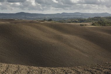 Tuscany, İtalya 'da hasat edilmiş tarlalar ve çayırlar. Sonbahar günbatımında dalgalı kır manzarası. Tarımsal mevsim için ekilebilir arazi hazır..