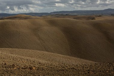 Tuscany, İtalya 'da hasat edilmiş tarlalar ve çayırlar. Sonbahar günbatımında dalgalı kır manzarası. Tarımsal mevsim için ekilebilir arazi hazır..