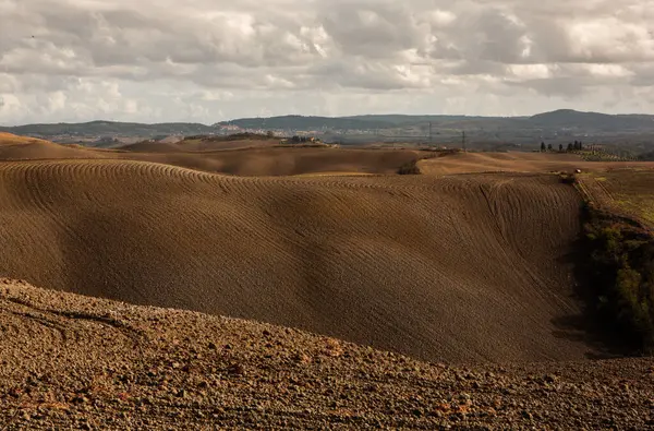 Tuscany, İtalya 'da hasat edilmiş tarlalar ve çayırlar. Sonbahar günbatımında dalgalı kır manzarası. Tarımsal mevsim için ekilebilir arazi hazır..