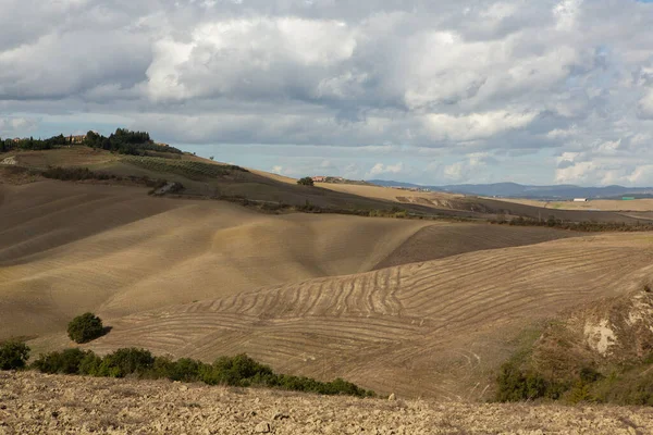 Tuscany, İtalya 'da hasat edilmiş tarlalar ve çayırlar. Sonbahar günbatımında dalgalı kır manzarası. Tarımsal mevsim için ekilebilir arazi hazır..