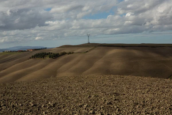 Tuscany, İtalya 'da hasat edilmiş tarlalar ve çayırlar. Sonbahar günbatımında dalgalı kır manzarası. Tarımsal mevsim için ekilebilir arazi hazır..