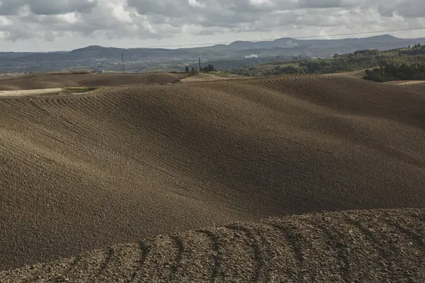 Tuscany, İtalya 'da hasat edilmiş tarlalar ve çayırlar. Sonbahar günbatımında dalgalı kır manzarası. Tarımsal mevsim için ekilebilir arazi hazır..