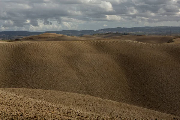 Tuscany, İtalya 'da hasat edilmiş tarlalar ve çayırlar. Sonbahar günbatımında dalgalı kır manzarası. Tarımsal mevsim için ekilebilir arazi hazır..