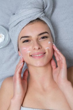 Beyaz tenli genç bir kız, kafasında havlu, güzellik konsepti fotoğrafı, cilt bakımı, spa konsepti, tedavi, yüz masajı.