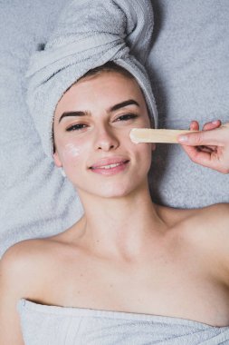 Beyaz tenli genç bir kız, kafasında havlu, güzellik konsepti fotoğrafı, cilt bakımı, spa konsepti, tedavi, yüz masajı.