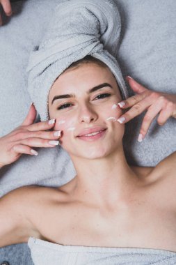 Beyaz tenli genç bir kız, kafasında havlu, güzellik konsepti fotoğrafı, cilt bakımı, spa konsepti, tedavi, yüz masajı.