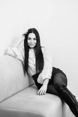 Beyaz gömlekli, uzun esmer saçlı ve gri arka planda siyah etekli bir iş kadını. Güzel bir esmerin siyah beyaz portresi