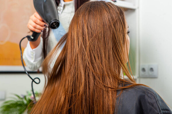 Photo of a European girl with long and beautiful brunette hair at the beauty salon. Shiny and healthy hair.