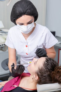 Diş hekiminde hasta dişlerini muayene eden bir diş hekimi. Diş sağlığı ve sağlık sigortası. Elinde diş aletleri tutan bir dişçi..