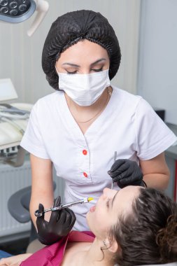 Diş hekiminde hasta dişlerini muayene eden bir diş hekimi. Diş sağlığı ve sağlık sigortası. Elinde diş aletleri tutan bir dişçi..