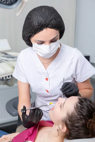 Diş hekiminde hasta dişlerini muayene eden bir diş hekimi. Diş sağlığı ve sağlık sigortası. Elinde diş aletleri tutan bir dişçi..