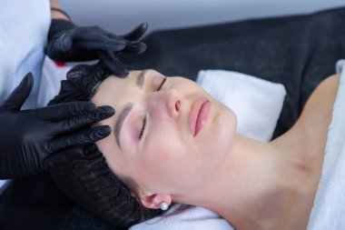 Genç ve güzel bir kadın güzellik salonunda yüz bakımı yaptırıyor. Güzellik tedavi konsepti.