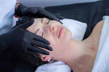 Genç ve güzel bir kadın güzellik salonunda yüz bakımı yaptırıyor. Güzellik tedavi konsepti.